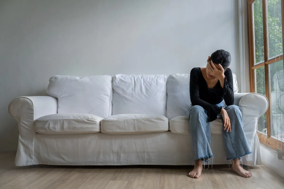 Frau sitzt auf Sofa und weint.